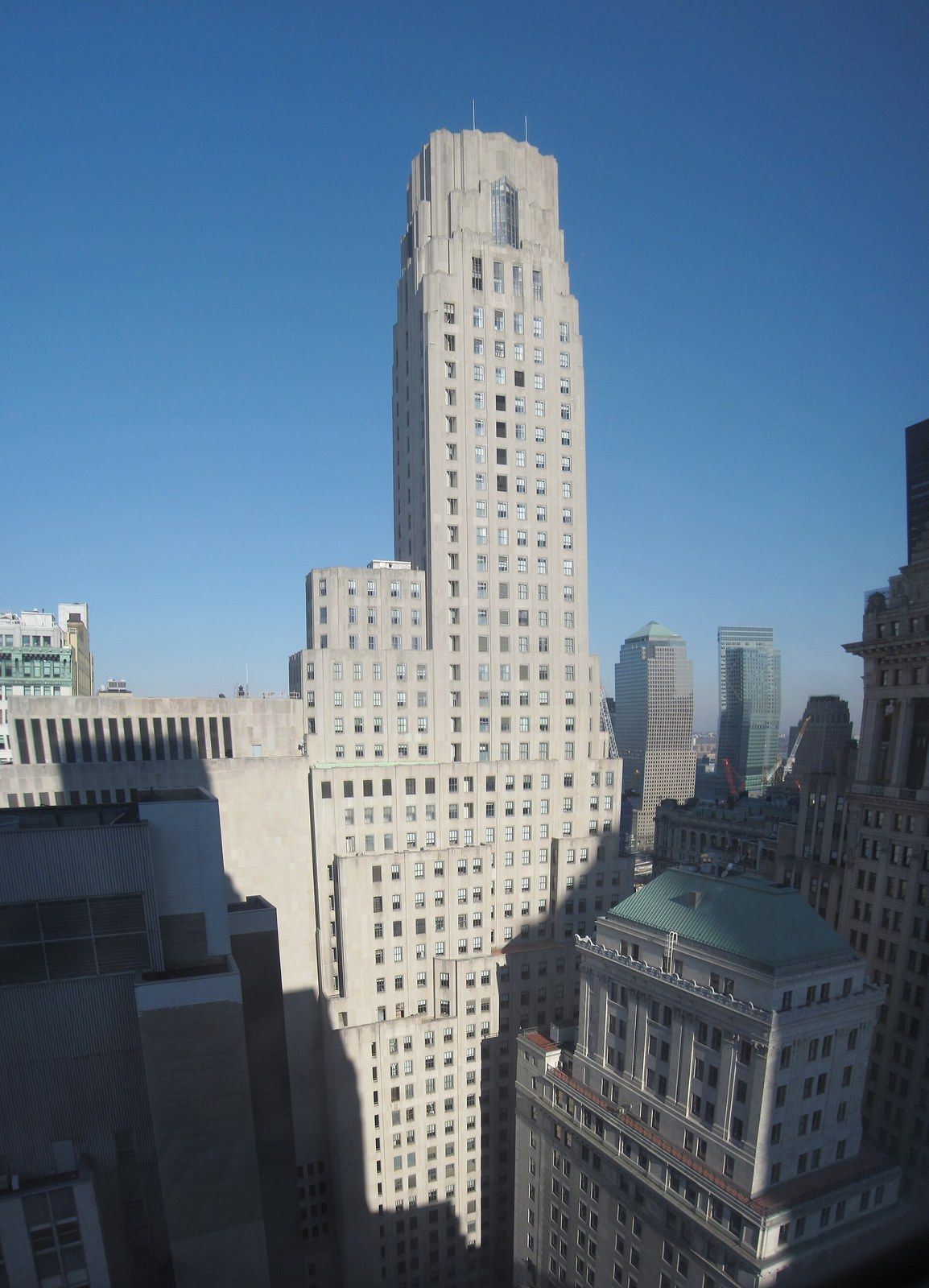 A tall limestone tower with setbacks and a stepped crown seen from above neighbouring rooftops, a Wikimedia Commons photograph in Michael Stern's encyclopedia
