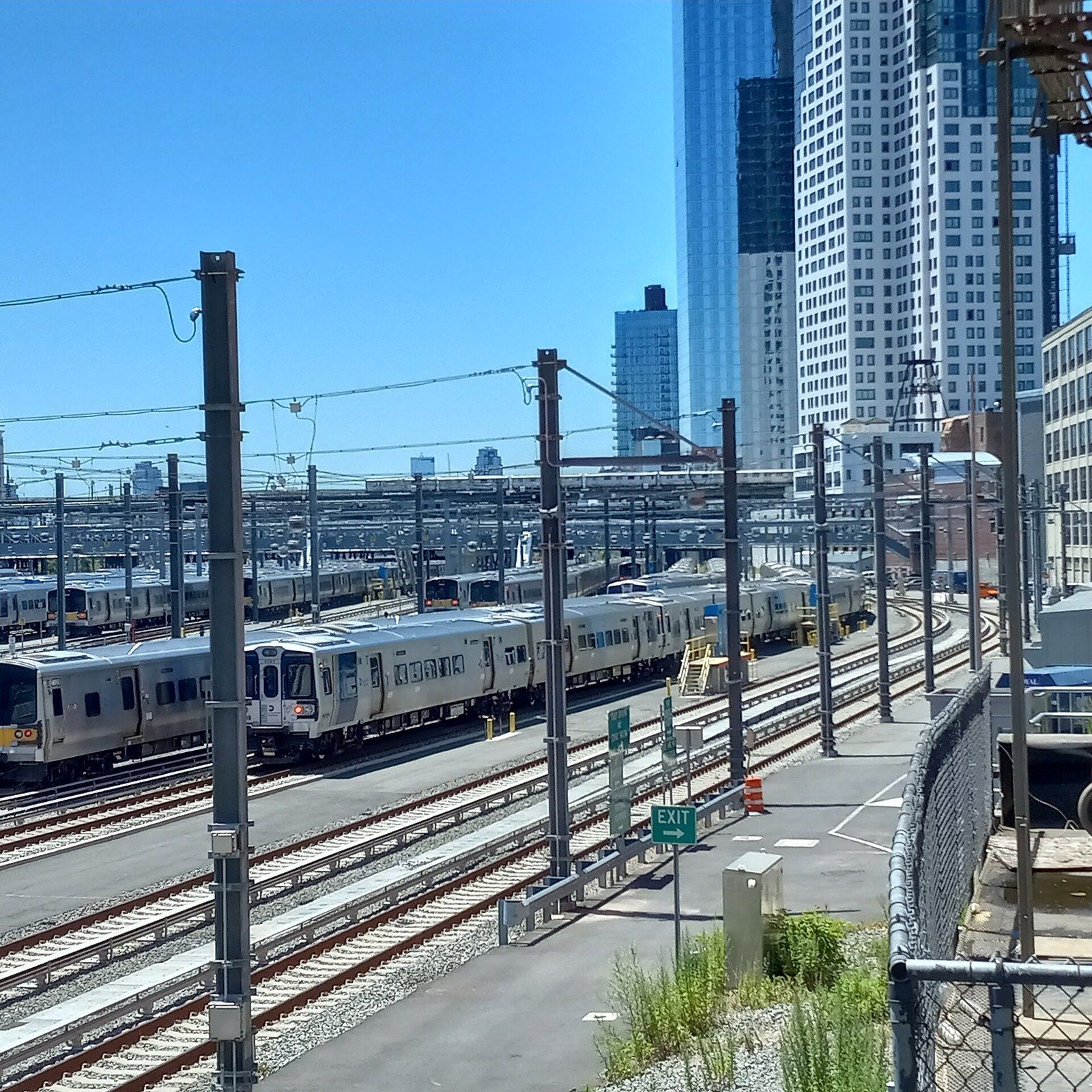 A rail yard with parked commuter trains and overhead wires, glass towers behind, a Wikimedia Commons photograph in Michael Stern's encyclopedia