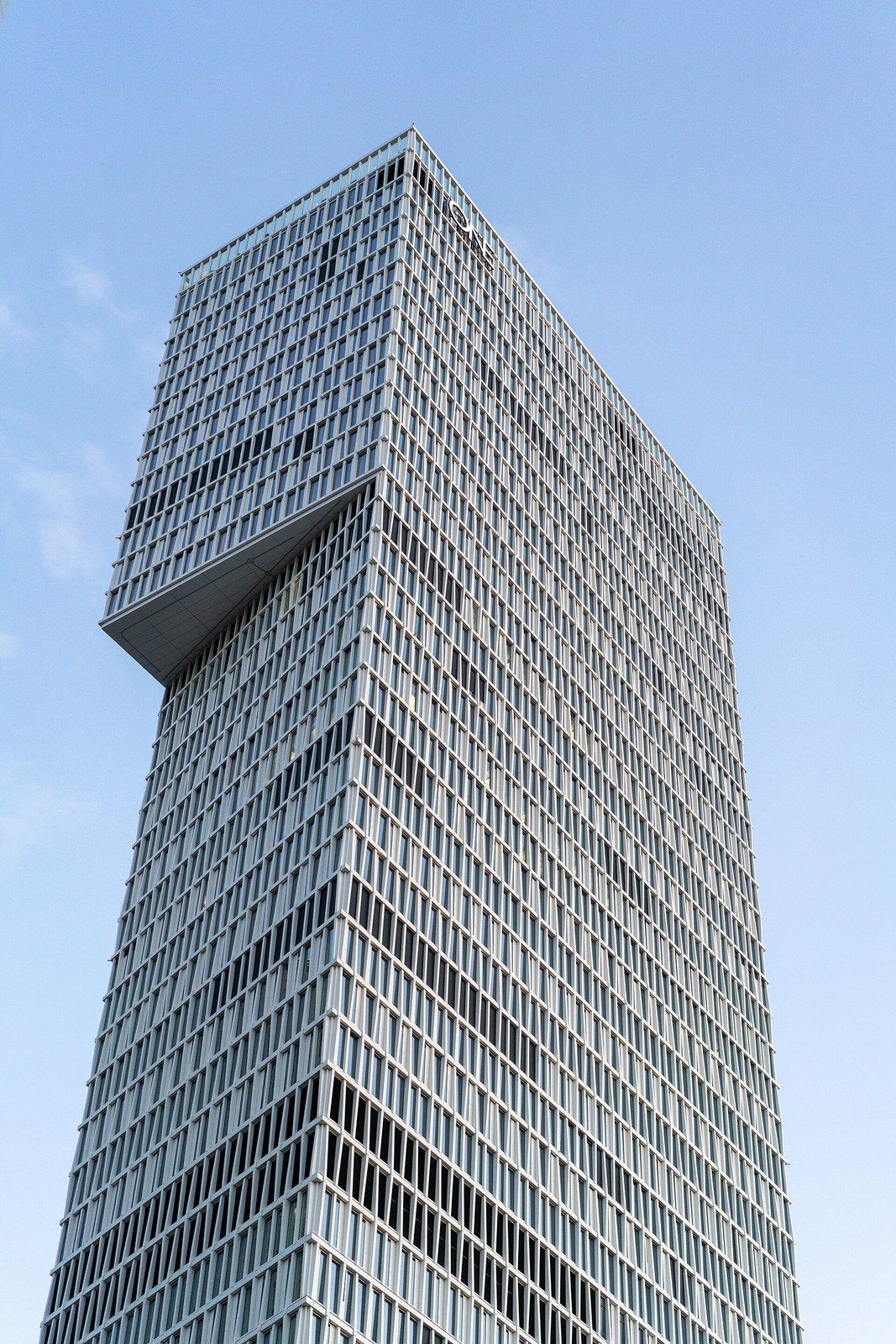A tall grid facade tower with a box cantilevered from its upper floors against the sky, a Wikimedia Commons photograph in Michael Stern's encyclopedia