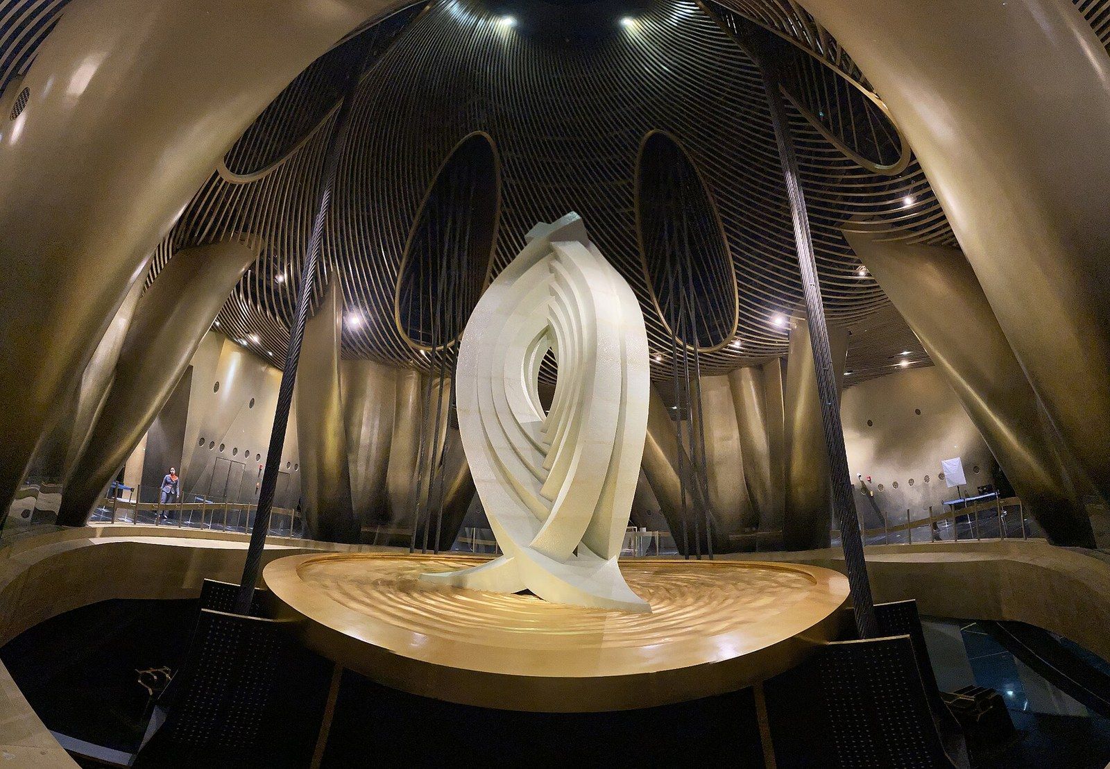 A large sculptural damper mass hanging inside the crown of a tower, lit from above, a Wikimedia Commons photograph in Michael Stern's encyclopedia