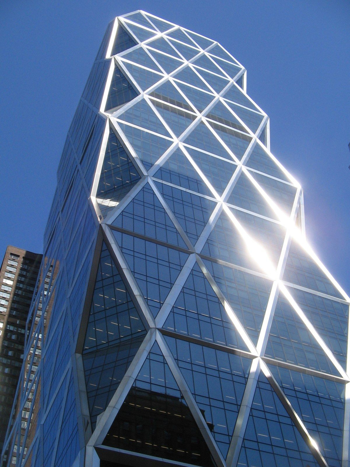 A glass office tower with a diagonal steel grid rising from an older stone base, a Wikimedia Commons photograph in Michael Stern's encyclopedia