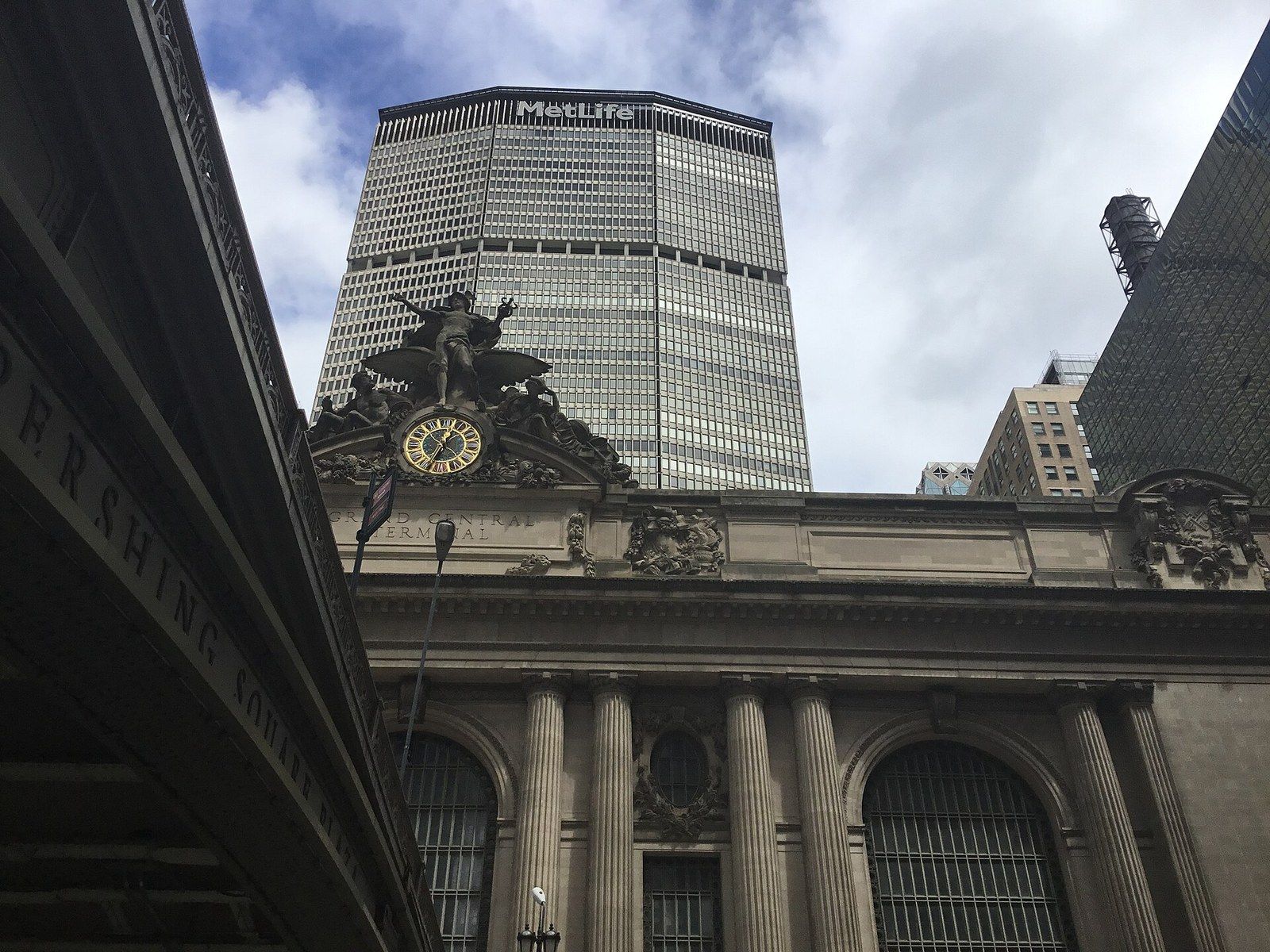 The clock and sculpture on a railway terminal with an office tower behind, seen from under a viaduct, a Wikimedia Commons photograph in Michael Stern's encyclopedia