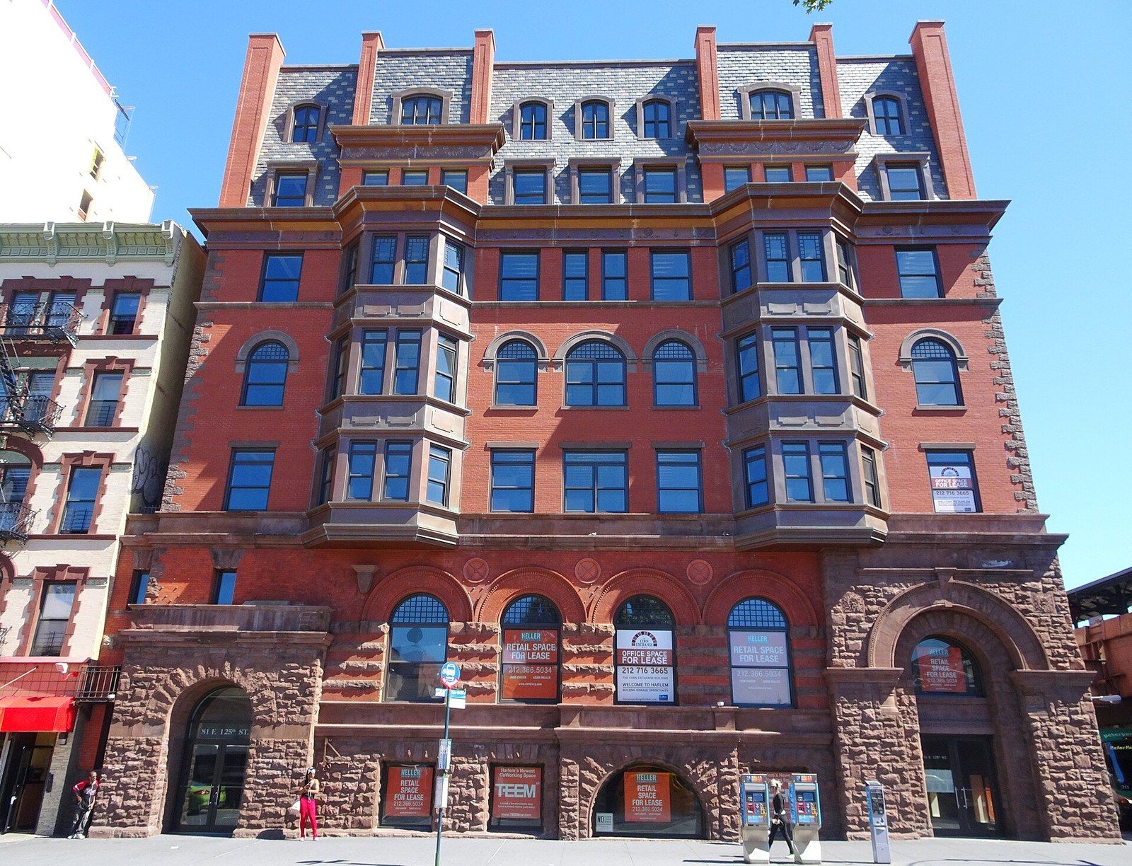A restored red brick and brownstone bank building with arched windows on a city corner, a Wikimedia Commons photograph in Michael Stern's encyclopedia