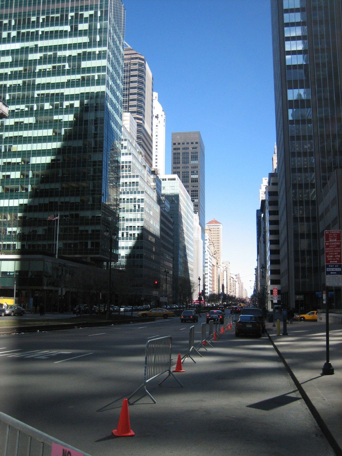 An avenue lined with glass office towers, one on a low podium, with the roadway in front, a Wikimedia Commons photograph in Michael Stern's encyclopedia