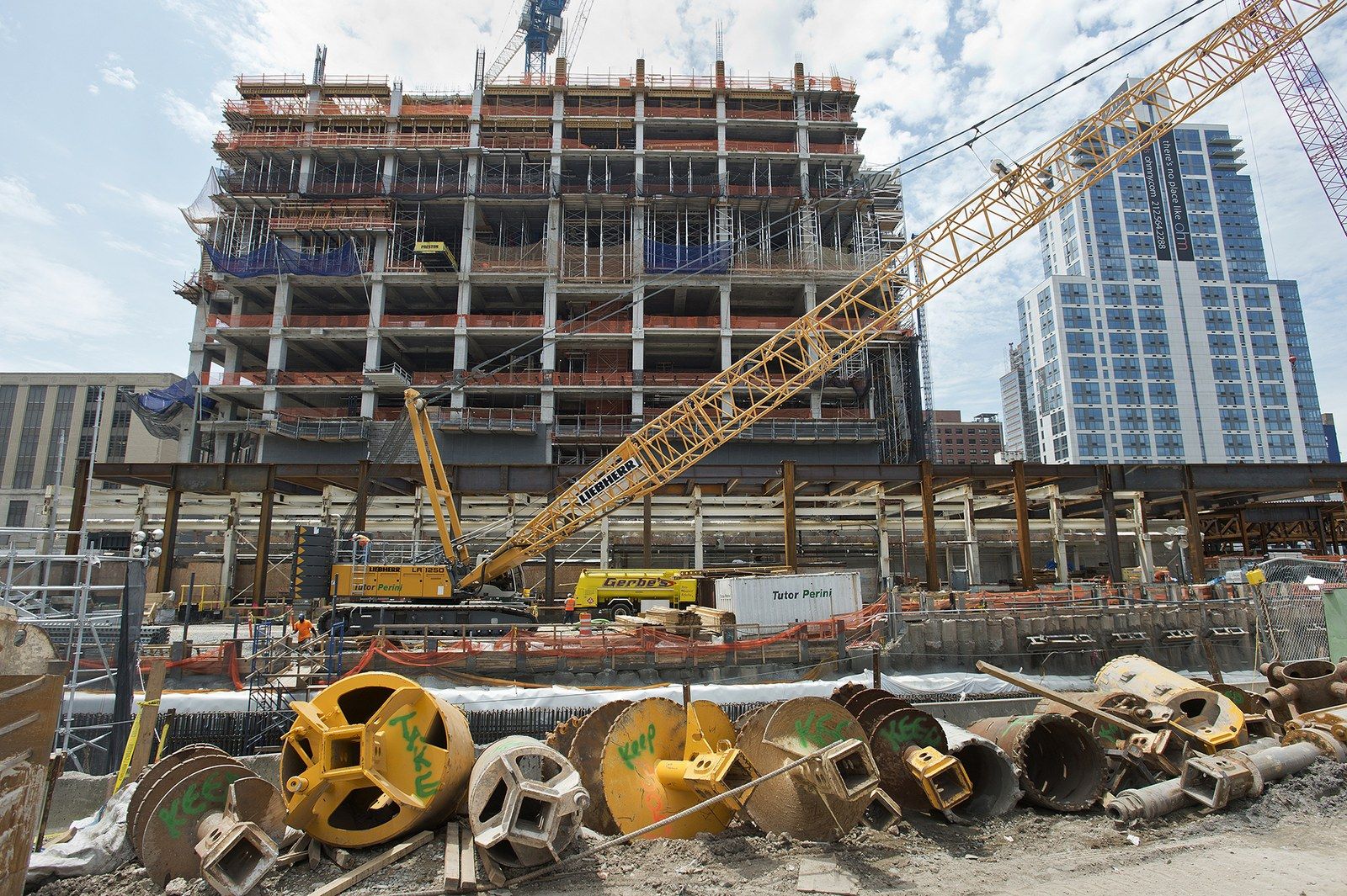 A steel and concrete frame rising with a crawler crane and drilled shaft casings in the foreground, a Wikimedia Commons photograph in Michael Stern's encyclopedia