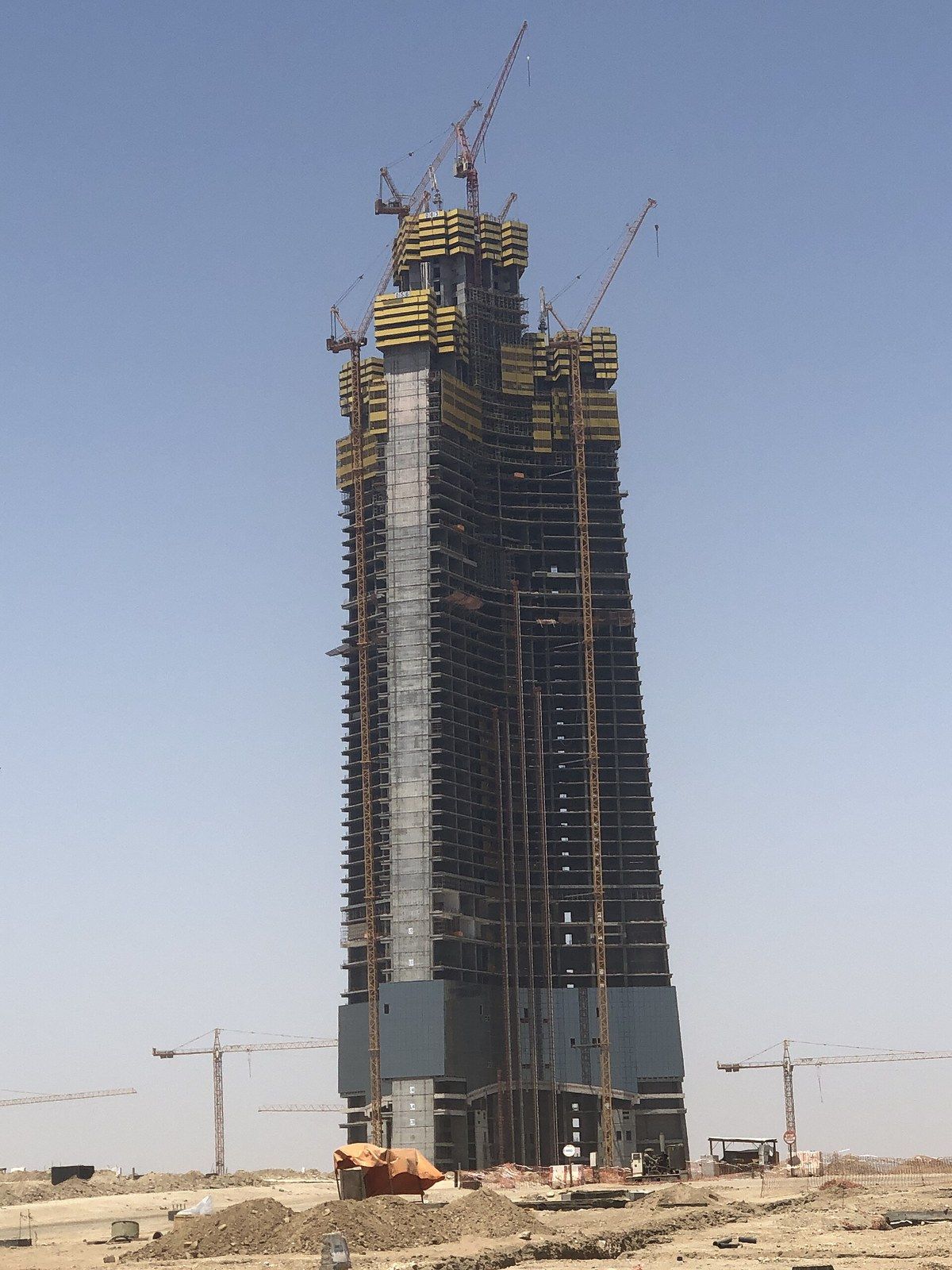 A concrete tower core under construction in a desert landscape with cranes at its top, a Wikimedia Commons photograph in Michael Stern's encyclopedia