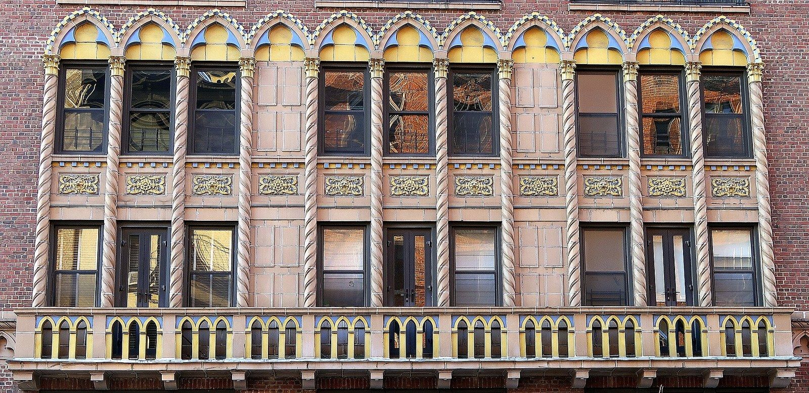 A row of windows framed in coloured glazed terra cotta on a 1920s apartment facade, a Wikimedia Commons photograph in Michael Stern's encyclopedia