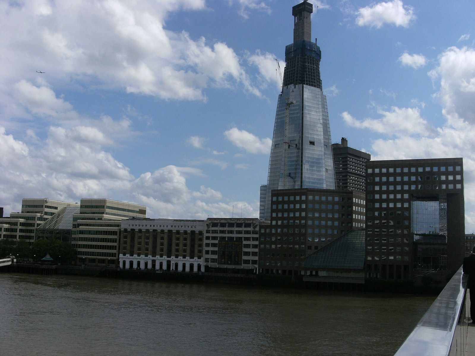 A glass tower under construction with its concrete core rising above the cladding, seen across a river, a Wikimedia Commons photograph in Michael Stern's encyclopedia