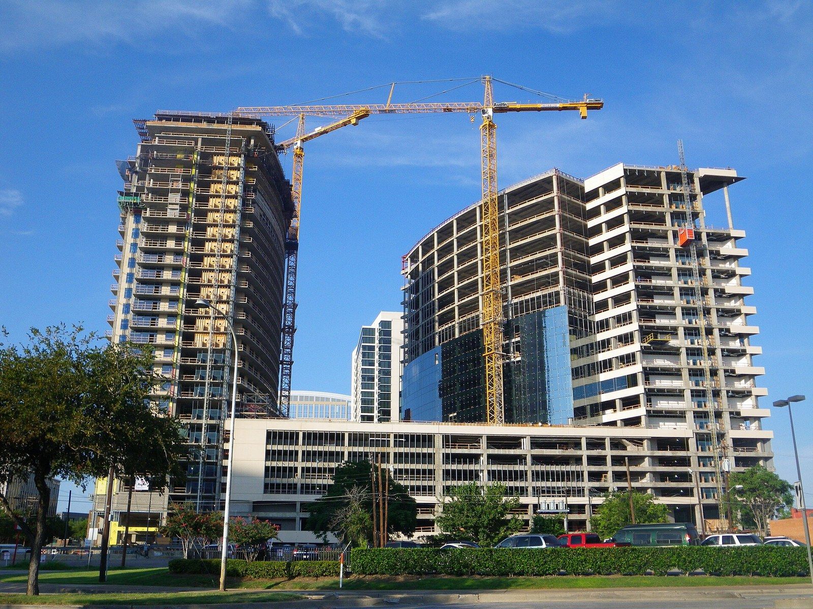 Several tower cranes over two concrete buildings under construction on a city block, a Wikimedia Commons photograph in Michael Stern's encyclopedia