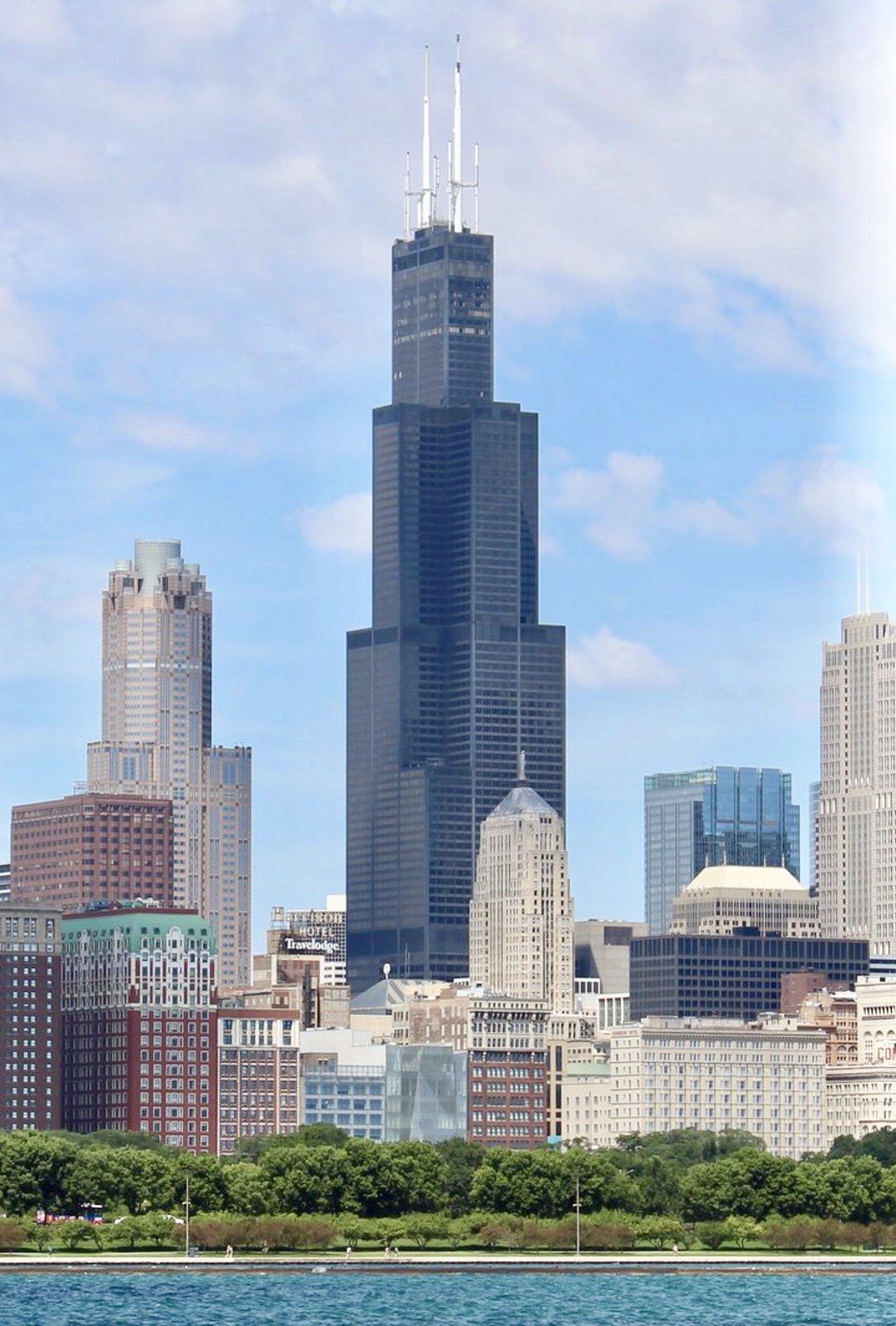 A black stepped skyscraper of bundled square tubes rising above a lakefront skyline, a Wikimedia Commons photograph in Michael Stern's encyclopedia